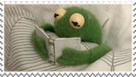 baby kermit reading a book in bed